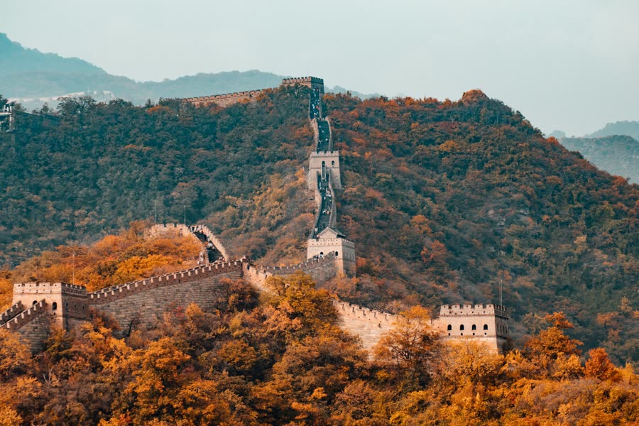 The Great Wall of China winding over forested mountains