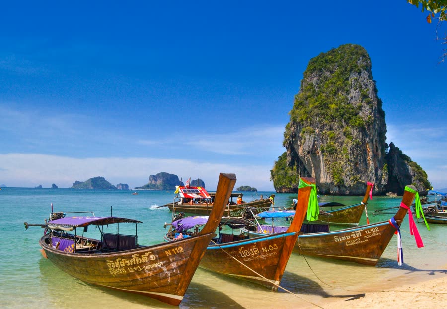 Wooden longtail boats moored in a turquoise Thai bay