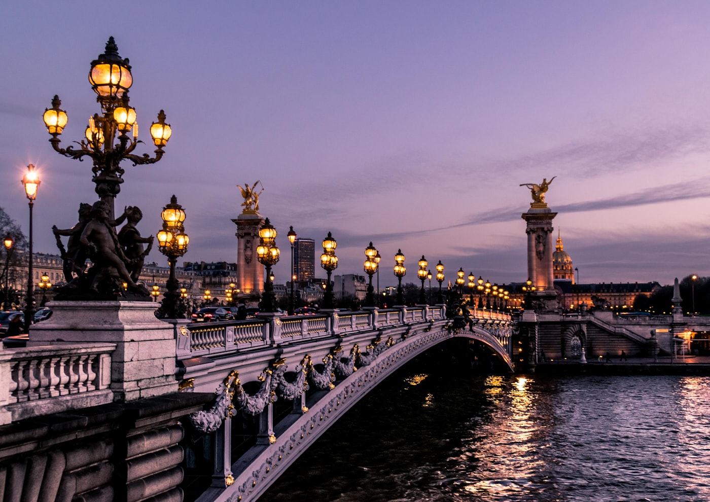 Gilded lamps along Pont Alexandre III at dusk with Les Invalides behind
